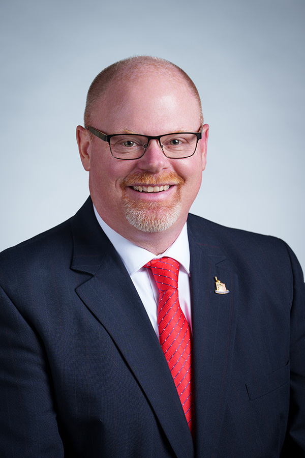 Chuck Heit standing in front of american flag
